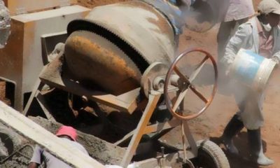 Workers mix cement at construction site.