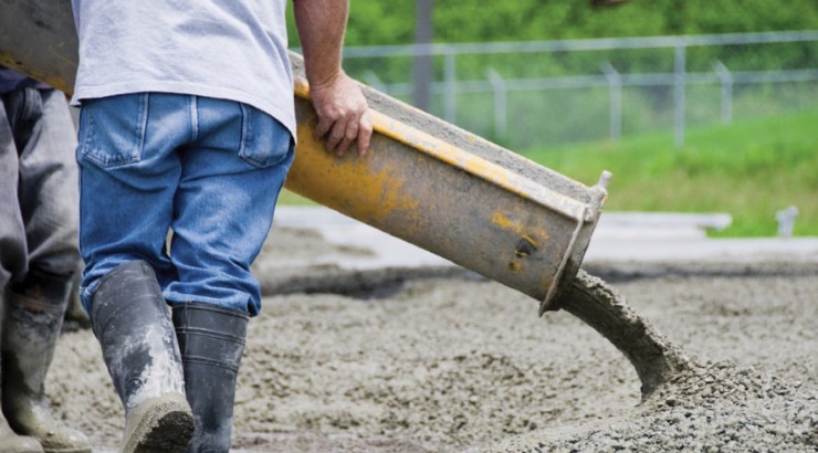 A worker pours concrete at construction site.