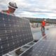 Workers arrange solar panels on-site.