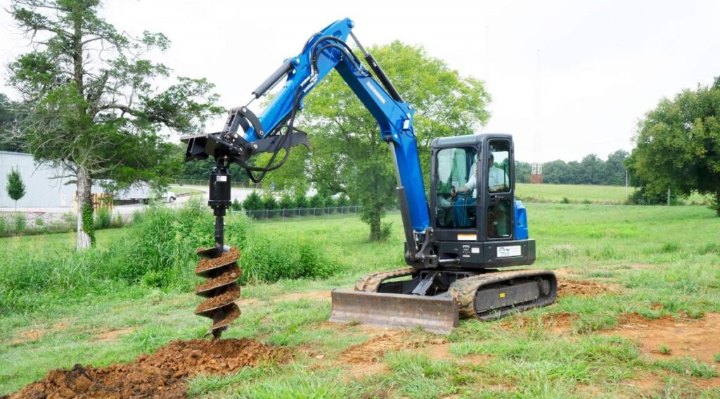 Auger attachment drilling a precise hole in the ground.