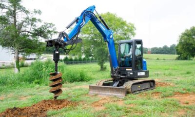 Auger attachment drilling a precise hole in the ground.