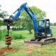 Auger attachment drilling a precise hole in the ground.