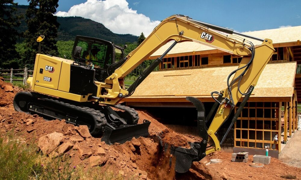 A Caterpillar 308CR mini excavator with long-stick attachment, shown on a construction site.