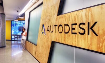 Woman standing in an Autodesk office workspace with modern desks, glass walls, and an open-plan design.